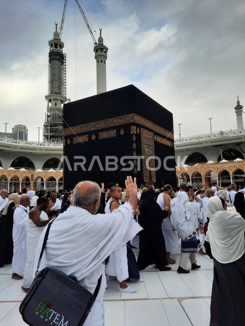 معالم دينية إسلامية مقدسة، صورة مقربة لحجاج بيت الله الحرام في الحرم المكي الشريف في المملكة العربية السعودية، الفن الهندسي المعماري لناطحات السحاب  في مكة المكرمة، العبادة والتقرب الى الله تعالى، منظر السماء الملبدة بالغيوم