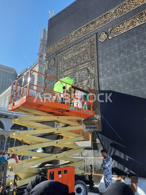 تغيير و استبدال كسوة الكعبة المشرفة القديم بثوب جديد, عمال يقفون على الرافعات لتبديل كسوة قبلة المسلمين, أداء المناسك و الفرائض الدينية, موسم الحج في المملكة العربيه السعودية، طواف حجاج بيت الله الحرام ،أماكن ومعالم اسلامية مقدسة
