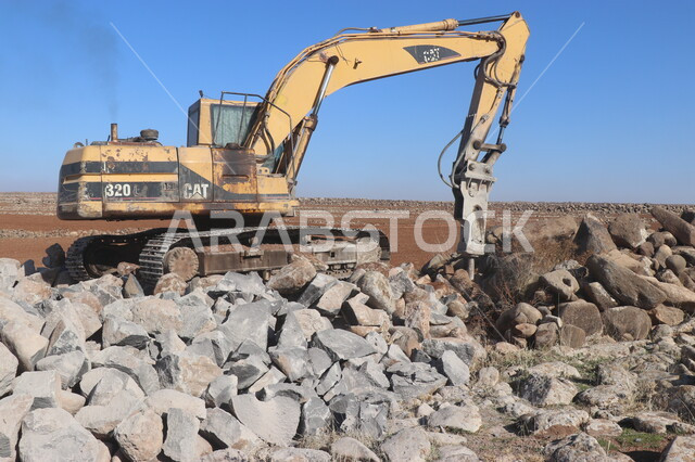 صورة مقربة لباكر يعمل على تكسير ونقر الصخور والحجار، مفهوم الهندسة والبناء والتطوير، مهن ووظائف هندسية في السعودية، قوة وتقنية عملية استخراج وتحطيم القطع الصخرية، آلات ومعدات ثقيلة