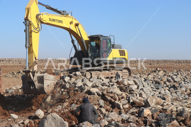 صورة مقربة لباكر يعمل على تكسير ونقر الصخور والحجار، مفهوم الهندسة والبناء والتطوير، مهن ووظائف هندسية في السعودية، قوة وتقنية عملية استخراج وتحطيم القطع الصخرية، آلات ومعدات ثقيلة