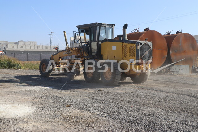 Machine for laying asphalt levelly on roads, paving main streets, concept of engineering, construction and development, engineering professions and jobs in Saudi Arabia, stone crushing plant and huge machines, power and technology of the process of extracting and crushing rocks, heavy machinery and equipment