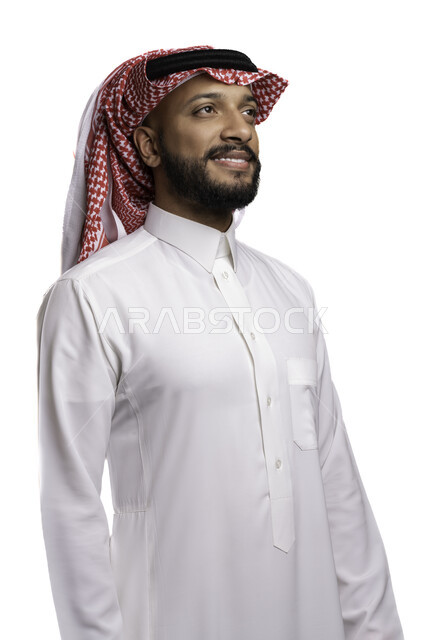 التفكير وشرود الذهن، مفهوم التأمل والتركيز، بورتريه مقرب لشاب عربي خليجي سعودي مبتسم يرتدي الشماغ والثوب التقليدي ينظرالى شيء ما، محاكاة النفس والذات، خلفية بيضاء