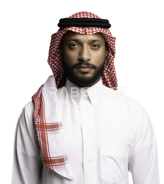 مفهوم الاناقة والرجولة، ألتقاط صور شخصية للوثائق الرسمية، بورتريه مقرب لشاب عربي خليجي سعودي يرتدي الشماغ والثوب التقليدي ينظر الى الكاميرا بتعابير الجدية والثقة بالنفس، الاعتناء والاهتمام بالمظهر الخارجي، خلفية بيضاء