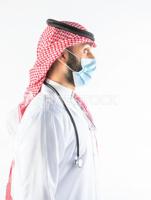 طبيبب سعودي يرتدي الكمامة ، اتباع اجراءات السلامة ، يقدم خدماته للمرضى بكل كفاءه  ، خلفية بيضاء، مفهوم الطب والرعاية الصحية