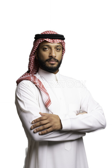 مفهوم الرجولة والثقة بالنفس، التركيز والتخطيط والتفكير لاتخاذ القرارات، الأناقة والاهتمام بالمظهر الخارجي، بورتريه لشاب عربي خليجي سعودي يرتدي الشماغ والثوب التقليدي ينظر الى الكاميرا بإيماءات الجدية والحزم,، خلفية بيضاء .