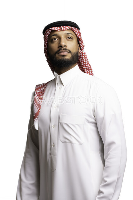 Focus and consideration to make decisions, elegance and attention to external appearance, thinking and planning to solve a problem, the concept of confusion and hesitation, a portrait of a Saudi Gulf Arab young man wearing a shemagh and traditional dress, looking at something with gestures of contemplation and absent-mindedness, a white background