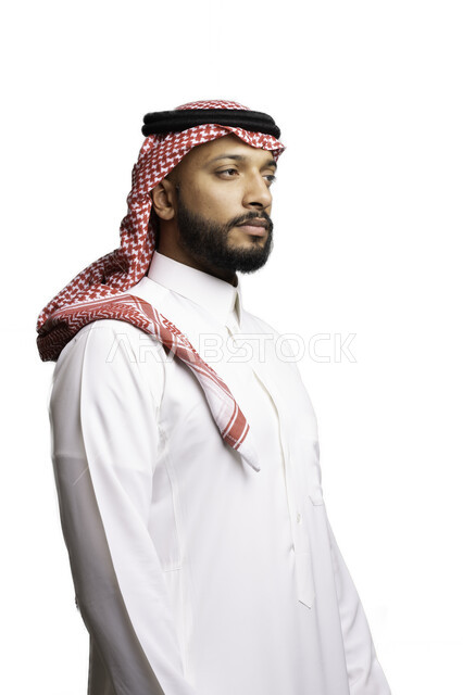 إيماءات الجدية والحزم, التركيز والتأمل لحل المشكلات, مفهوم التردد والحيرة، التخطيط والتفكير لاتخاذ القرارات، الأناقة والاهتمام بالمظهر الخارجي، بورتريه لشاب عربي خليجي سعودي يرتدي الشماغ والثوب التقليدي ينظر الى شيء ما ، خلفية بيضاء .