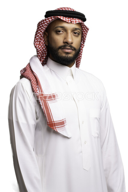 الاهتمام بالأناقة والمظهر الخارجي، التفكير والتخطيط لحل مشكلة ما، التمعن والتركيز لاتخاذ القرارات، مفهوم الحيرة والتردد، بورتريه لشاب عربي خليجي سعودي يرتدي الشماغ والثوب التقليدي ينظر الى شيء ما بإيماءات التأمل وشرود الذهن، خلفية بيضاء .