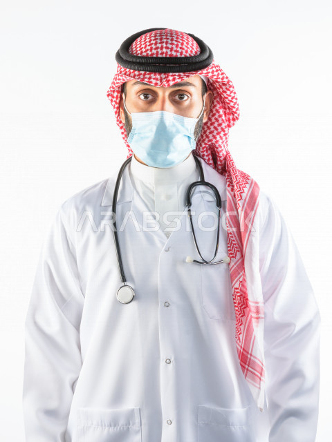 طبيبب سعودي يرتدي الكمامة ، اتباع اجراءات السلامة ، يقدم خدماته للمرضى بكل كفاءه  ، خلفية بيضاء، مفهوم الطب والرعاية الصحية