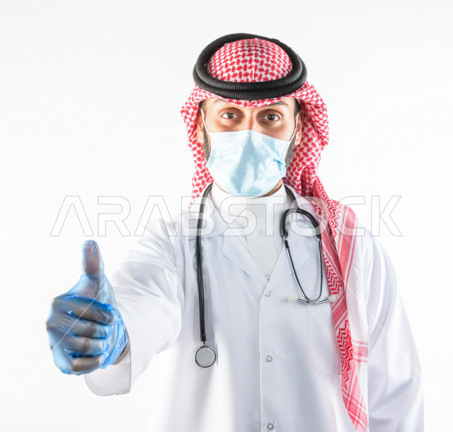 طبيبب سعودي يرتدي الكمامة ، اتباع اجراءات السلامة ، يقدم خدماته للمرضى بكل كفاءه  ، خلفية بيضاء، مفهوم الطب والرعاية الصحية