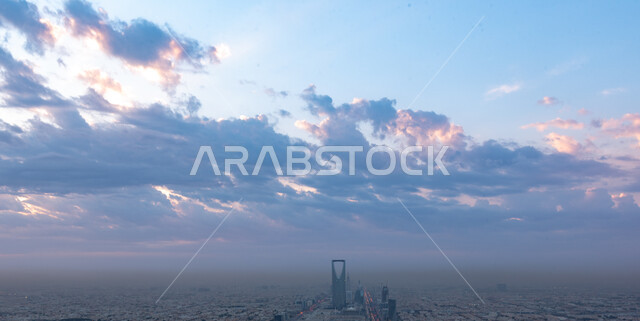 Attracting foreign tourists to famous landmarks and places, the advanced and modern design of towers and skyscrapers, the architectural engineering art of the Kingdom Tower in the city of Riyadh, a picture from the top of buildings and residential facilities during the day in Saudi Arabia, the background of the sky full of white clouds