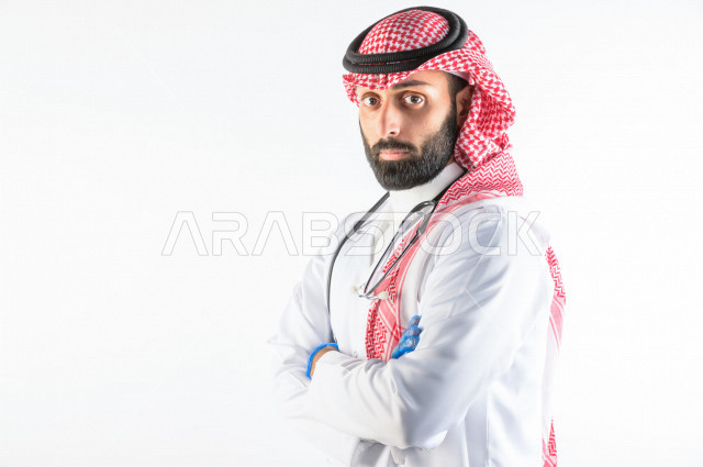 بورتريه لطبيبب سعودي خليجي مبتسم و ينظر للكاميرا ، يقدم خدماته للمرضى بكل كفاءه  ، خلفية بيضاء، مفهوم الطب والرعاية الصحية