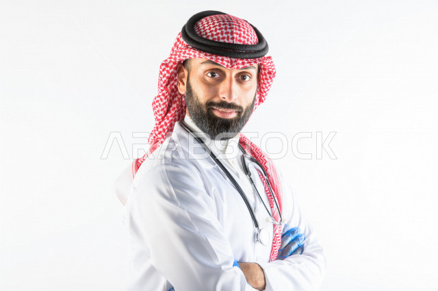 بورتريه لطبيبب سعودي خليجي مبتسم و ينظر للكاميرا ، يقدم خدماته للمرضى بكل كفاءه  ، خلفية بيضاء، مفهوم الطب والرعاية الصحية