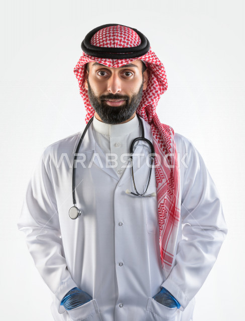 بورتريه لطبيبب سعودي خليجي مبتسم و ينظر للكاميرا ، يقدم خدماته للمرضى بكل كفاءه  ، خلفية بيضاء، مفهوم الطب والرعاية الصحية