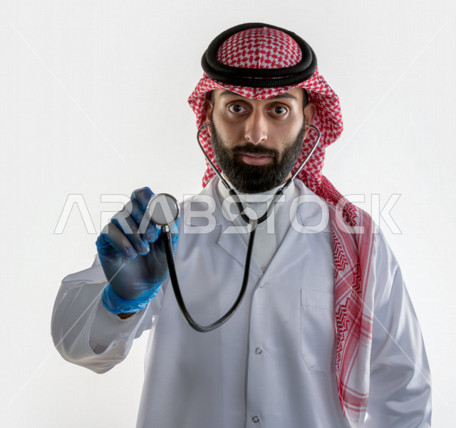 بورتريه لطبيبب سعودي خليجي مبتسم و ينظر للكاميرا ، يقدم خدماته للمرضى بكل كفاءه  ، خلفية بيضاء، مفهوم الطب والرعاية الصحية