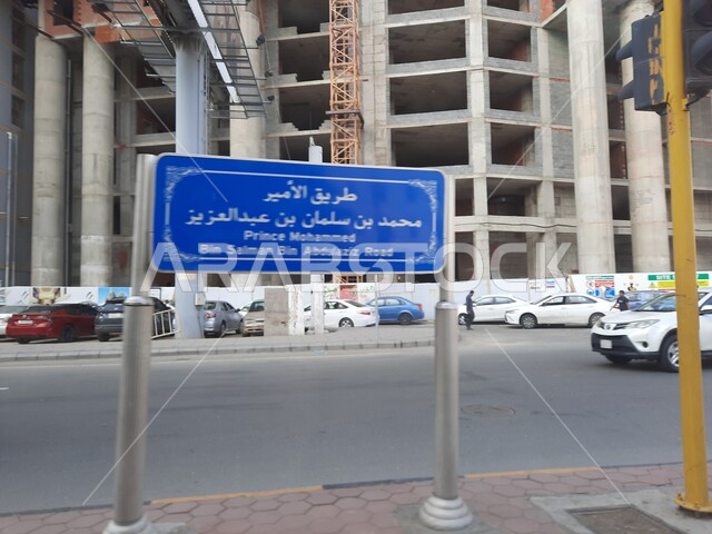 An explanatory sign for Prince Mohammed bin Salman bin Abdulaziz Road, sacred Islamic religious landmarks and places, interest in construction and urban development in Mecca, car traffic on paved roads and streets in the Kingdom of Saudi Arabia, luxury hotels and towers surrounding the Grand Mosque