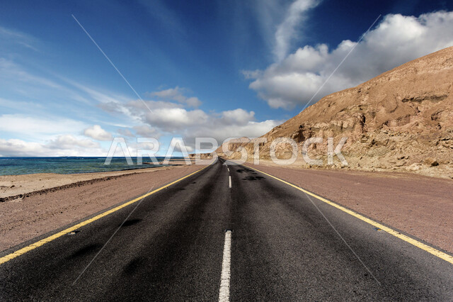 طريق اسفلتي سريع في المناطق الصحراوية، منظر الغيوم البيضاء في سماء محافطة العلا، القمم والمرتفعات الجبلية والطبيعة الصحراوية، اماكن سياحية طبيعية في  المملكة العربية السعودية