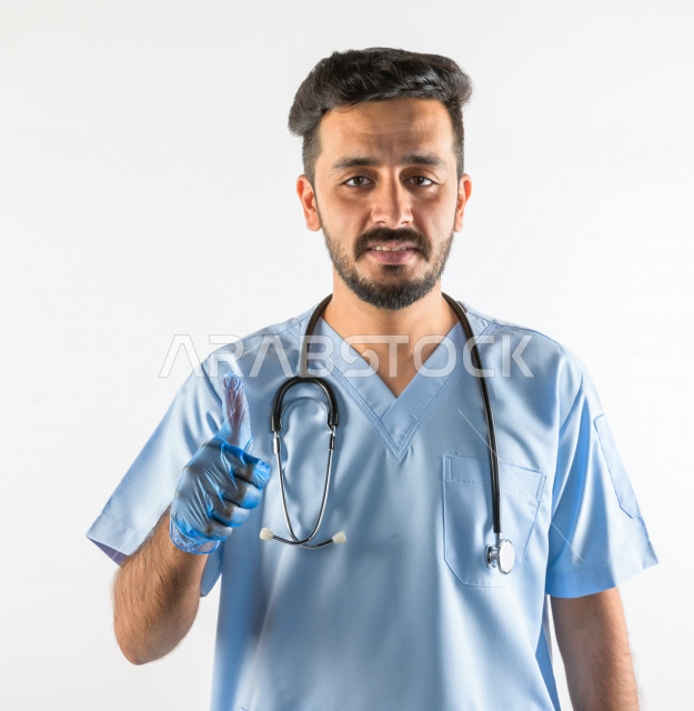 بورتريه لطبيبب سعودي خليجي مبتسم و ينظر للكاميرا ، يقدم خدماته للمرضى بكل كفاءه  ، خلفية بيضاء، مفهوم الطب والرعاية الصحية