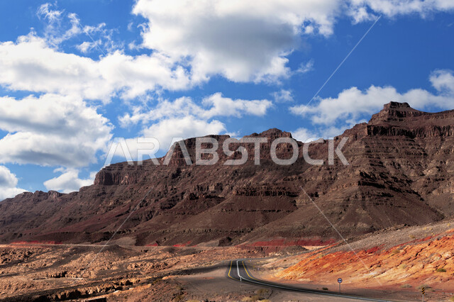 Famous tourist attractions, mountain roads in high altitude areas, terrain, mountains and peaks in the daytime, the view of the sky filled with white clouds.  Tourism in the city of Tabuk in the Kingdom of Saudi Arabia