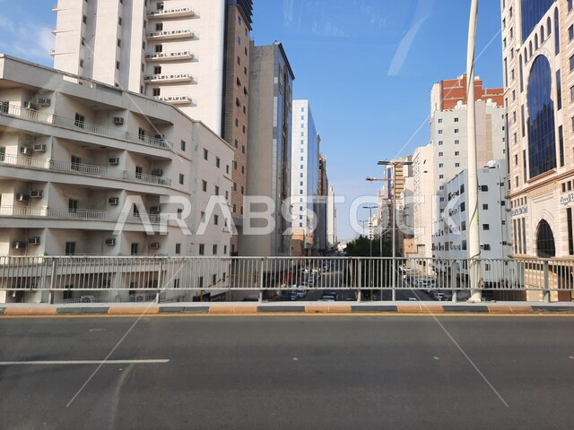 Interest in construction and urban development in Mecca, car movement on paved roads and streets in the Kingdom of Saudi Arabia, Prince Mohammed bin Salman bin Abdulaziz Road, sacred Islamic religious landmarks and places, luxury hotels and towers surrounding the Grand Mosque.