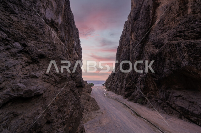  طريق اسفلتي صغير بين جبلين مرتفعين وقت غروب الشمس، معالم اثرية تاريخية قديمة، اماكن سياحية مشهورة في المملكة العربية السعودية، المحميات الطبيعية الصحراوية، سلسلة الجبال والتكوينات والتشكلات الصخرية في منطقة تبوك