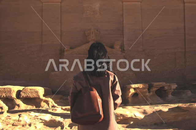 التعرف على التاريخ والأصالة والعراقة ,صورة من الخلف لسائحة تتأمل متحف العلا الثقافي في وضح النهار، الطبيعة الصحراوية في المملكة العربية السعودية, أماكن طبيعية تاريخية لجذب واستقطاب السائحين الى السعودية, التكوينات والتشكيلات الصخرية في محافظة العلا التراثية