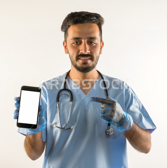 بورتريه لطبيبب سعودي خليجي مبتسم و يستخدم هاتفه المحمول  ،  الاتصال و التواصل عن بعد ، يقدم خدماته للمرضى بكل كفاءه  ، خلفية بيضاء، مفهوم الطب والرعاية الصحية