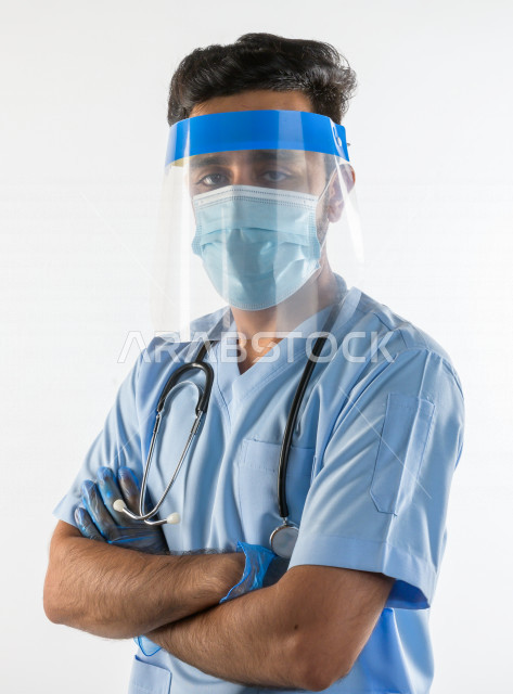 طبيبب سعودي يرتدي معدات وقائية لمكافحة فيروس كورونا   ، يرتدي قناع الوجه ، القناع البلاسيتكي الوقائي ، اتباع اجراءات السلامة  ، تجنب انتشار العدوى ، خلفية بيضاء، مفهوم الطب والرعاية الصحية