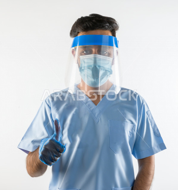 طبيبب سعودي يرتدي معدات وقائية لمكافحة فيروس كورونا   ، يرتدي قناع الوجه ، القناع البلاسيتكي الوقائي ، اتباع اجراءات السلامة  ، تجنب انتشار العدوى ، خلفية بيضاء، مفهوم الطب والرعاية الصحية