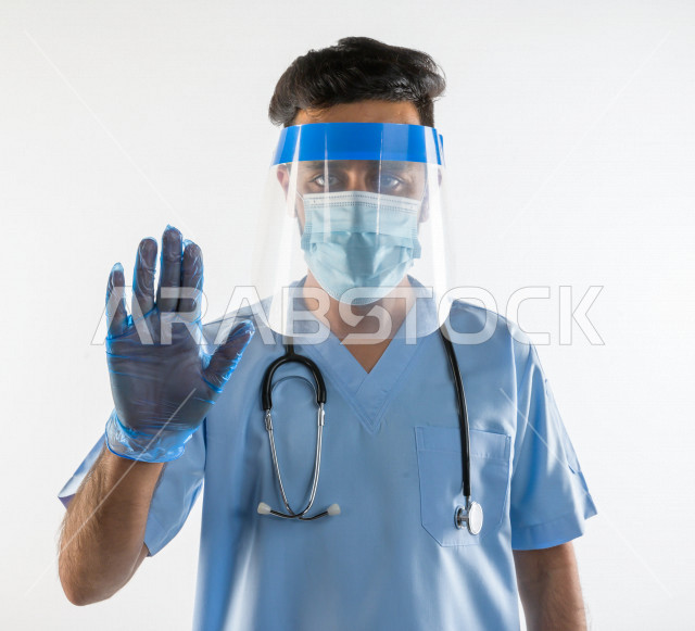 A Saudi doctor wears protective equipment to combat Corona virus, wears a face mask, a protective plastic mask, follows safety measures, avoids the spread of infection, white background, medicine and healthcare concept