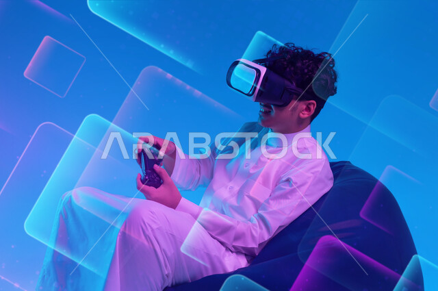 دمج التسلية مع الواقع الافتراضي والخيالي، استخدام الأجهزة التكنولوجية والتقنيات الحديثة، بورتريه لشاب عربي خليجي سعودي يرتدي الثوب التقليدي ونظارة في آر يجلس على كرسي مريح يمسك عصا التحكم يقوم باللعب في ألعاب الفيديو الترفيهية، خلفية زرقاء مع مكعبات ثري دي