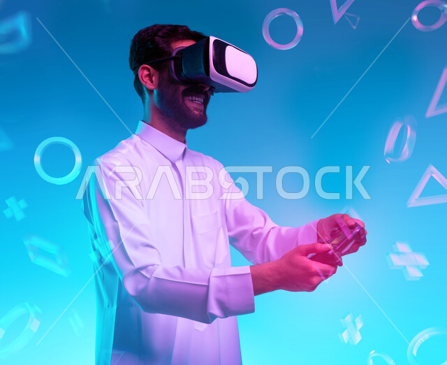 أجهزة تكنولوجية وتقنيات حديثة، دمج المتعة والتسلية مع العالم الافتراضي، بورتريه مقرب لشاب عربي خليجي سعودي يرتدي الثوب التقليدي ونظارة الفي آر يمسك بيده عصا التحكم يقوم باللعب في ألعاب الفيديو الترفيهية، قضاء اوقات فراغ ممتعة، خلفية زرقاء بأيقونات أزرار التنقل