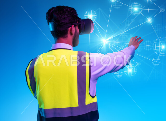 العمل بالقطاع الهندسي عبر تقنية الواقع الافتراضي، استخدام خاصية الهولوجرام ثلاثية الأبعاد، بورتريه مقرب من الخلف لمهندس عربي خليجي سعودي يرتدي سترة الحماية ونظارة الفي آر، استخدام التكنولوجيا في المجالات الهندسية، التفاعل مع الأيقونات الافتراضية، خلفية زرقاء