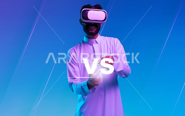 أجهزة تكنولوجية وتقنيات حديثة، دمج المتعة والتسلية مع العالم الخيالي، بورتريه مقرب لشاب عربي خليجي سعودي مبتسم يرتدي الثوب التقليدي ونظارة الواقع الإفتراضي يمسك بيده عصا التحكم يقوم باللعب في ألعاب الفيديو الترفيهية، قضاء اوقات فراغ ممتعة، خلفية زرقاء