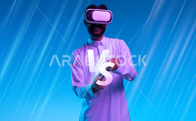 دمج المتعة والتسلية مع العالم الخيالي، شاب عربي خليجي سعودي مبتسم يرتدي الثوب التقليدي ونظارة الواقع الإفتراضي يمسك بيده عصا التحكم يقوم باللعب في ألعاب الفيديو الترفيهية، أجهزة تكنولوجية وتقنيات حديثة، قضاء اوقات فراغ ممتعة، خلفية زرقاء