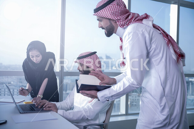 تطوير الاستراتيجيات وتبادل الأفكار والخبرات لتحقيق أهداف العمل، التعاون وروح الفريق الواحد، زملاء عمل عرب خليجيون سعوديون في اجتماع مكتبي, مناقشة وتنظيم الاعمال باستخدام جهاز الحاسوب المحمول، دمج العمل مع التقنية والتكنولوجيا، خلفية المكتب ضمن مقر الشركة