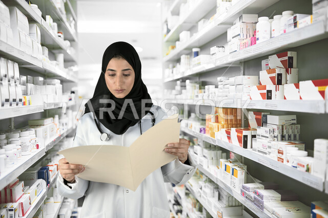 مكونات التركيبة الدوائية, مفهوم الصيدلة والرعاية الصحية، الادوية والمستلزمات الطبية، مهن ووظائف نسائية, التشييك على قائمة الأدوية, طبيبة صيدلانية عربية خليجية سعودية ترتدي المعطف الطبي الأبيض وسماعة الفحص تقوم بقراءة الوصفات العلاجية, خلفية الصيدلية