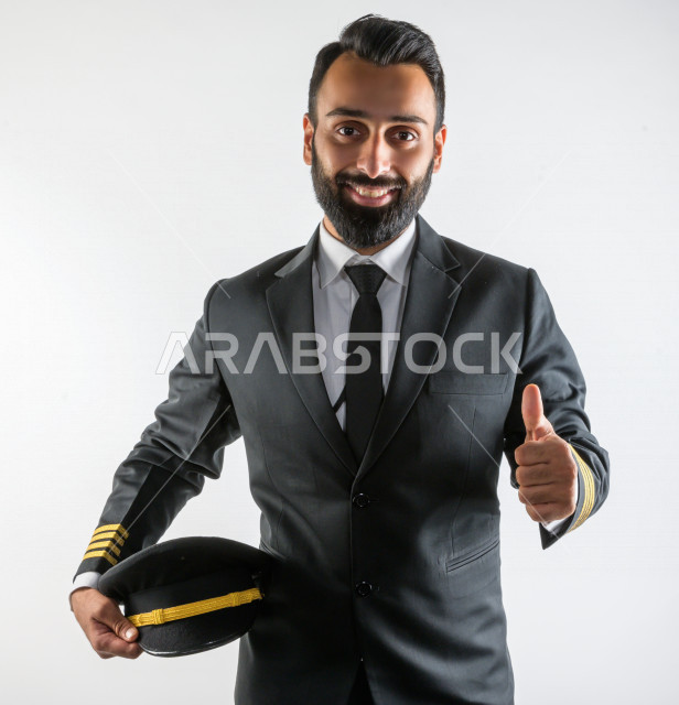بورتريه لكابتن طيار سعودي خليجي ناجح  ، يعمل في مجال الطيران ، يرتدي الزي الرسمي الخاص بمزاولة مهنة الطيران ، خلفية بيضاء