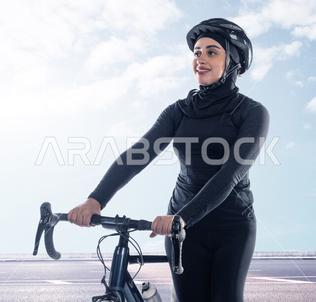 السعادة بالقيام بنشاط بدني للمحافظة على اللياقة الجسدية، جودة الحياة الصحية، شابة عربية خليجية سعودية مبتسمة ترتدي الملابس الرياضية وخوذة الحماية تقوم بممارسة رياضة ركوب الدراجة الهوائية في الهواء الطلق، أنشطة ورياضات نسائية في المملكة، خلفية الغيوم في السماء