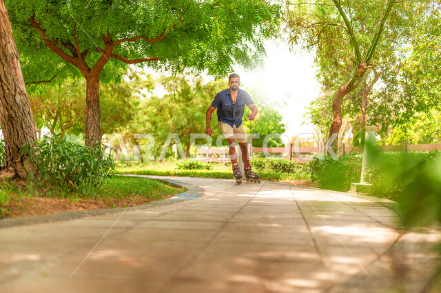 رجل عربي خليجي سعودي يرتدي الزلاجات الدوارة في إحدى الحدائق الترفيهية بالمملكة العربية السعودية، أماكن سياحية ترفيهية، قضاء أوقات ممتعة، ممارسة رياضة التزلج بالعجلات على طريق مخصص للمشي، الطبيعة الخضراء المتيزة