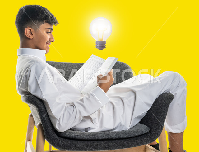 قضاء الوقت بالقراءة والتعلم والتثقف ، بورتريه لشاب عربي سعودي خليجي يرتدي الزي السعودي يجلس على كرسي مريح ويحمل بيديه كتاب، لمبة صفراء مضيئة, مفهوم التعليم الذاتي, أفكار إبداعية تطويرية, خلفية صفراء