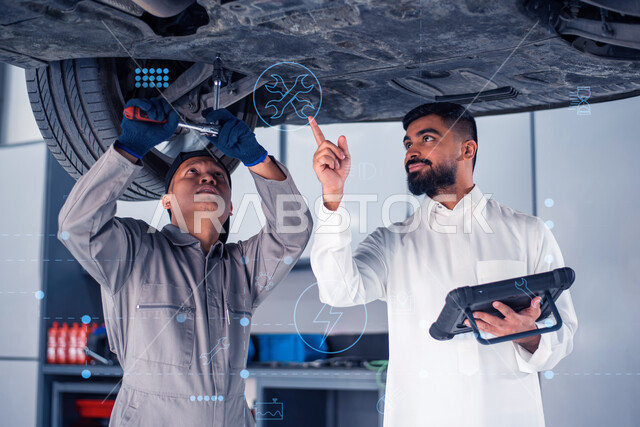 Car construction and repair in the maintenance center, a professional mechanical engineer detects and repairs car malfunctions via a tablet device, a Filipino maintenance worker repairs a Saudi Arabian Gulf customer’s car in the workshop, using modern devices and technologies at work