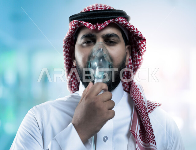 Treating cases of shortness of breath, ensuring comfort for the respiratory muscles using a respirator, a close-up picture of a Saudi Arabian Gulf man wearing a shemagh and traditional thobe, putting on a spray mask to inhale oxygen, providing home health services to the patient, blurry background