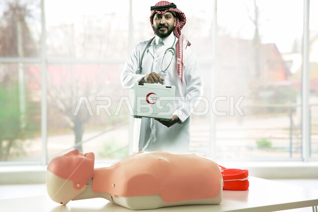 دمية احترافية للتدريب على الاسعافات الاولية، مبادئ التعامل مع حالات الطوارئ، تقديم الخدمات الصحية الطارئة للمرضى، طبيب عربي سعودي خليجي يرتدي الشماغ والمعطف الطبي يحمل بيده حقيبة الأدوات والمعدات الطبية اللازمة، العمل في القطاع الصحي