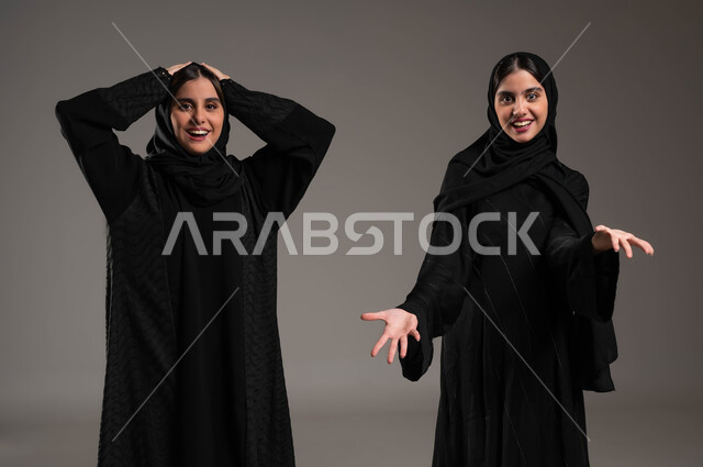 الشعور بالدهشة والذهول, ايماءات تدل على الحماس والاستغراب, بورتريه مقرب لبنتان عربيتان سعوديتان خليجيتان ترتديان الحجاب والعباءة احداهما تضع يدها على رأسها والاخرى في حالة حيرة, خلفية رمادية