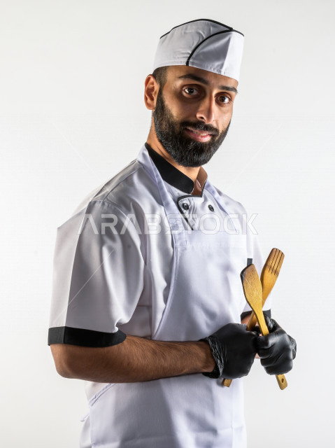 بورتريه لشيف طباخ سعودي خليجي خبير و ناجح  في العمل، يعمل في مجال الطبخ و الفندقة ، يرتدي الزي الرسمي الخاص بمزاولة مهنة الطباخ ، خلفية بيضاء