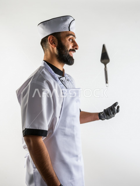 بورتريه لشيف طباخ سعودي خليجي خبير و ناجح  في العمل، يعمل في مجال الطبخ و الفندقة ، يرتدي الزي الرسمي الخاص بمزاولة مهنة الطباخ ، خلفية بيضاء