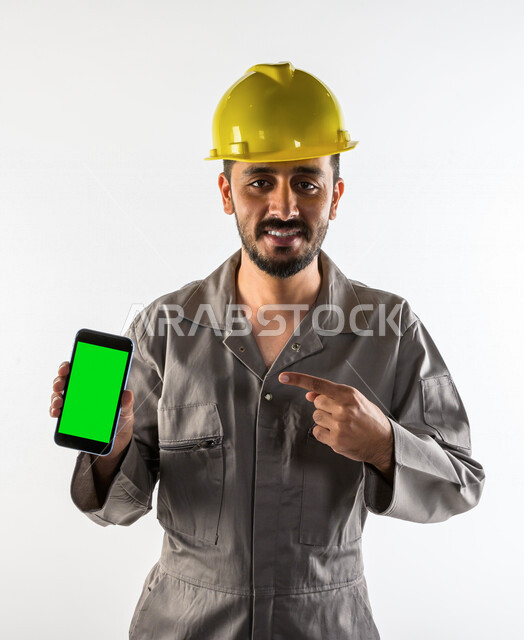 بورتريه لشاب سعودي خليجي يعمل كمهندس فني ، يستخدم هاتف المحمول بخلفية خضراء كروما ، يزاول مهنته باحتراف ، المهارة و اتقان العمل ، عامل بناء محترف ، حرفي كهربائي ، الأعمال و الصيانة ، خلفية بيضاء