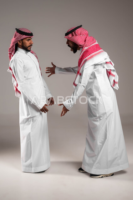 ايماءات الصراخ و التوبيخ، بورتريه لرجلان توءم عربيان خليجيان سعوديان يقفان مقابل بعضهما، الغضب والقاء اللوم، النقاش والمواجهة بين الأخوة، تأثير العواطف السلبية بين الأخوات ،الضغط العصبي و التوتر، صور الجسم بالطول الكامل، خلفية بيضاء