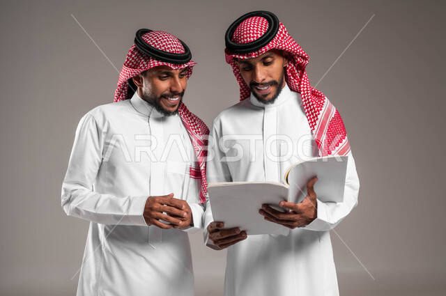 ثقافة التعلم الذاتي، مراجعة الدروس اليومية، ثقافة التعلم الذاتي، الاستمتاع بممارسة هواية المطالعة، بورتريه مقرب لشابين توءم عربيين خليجيين سعوديين  مبتسمتين يقضيان وقتهما بالقراءة والتثقف، خلفية رمادية